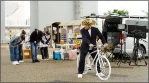 撮影の仕事を終えて、自転車に乗る松平健さんを、撮影スタッフが見送る