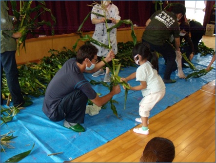 園児にトウモロコシを収穫させるクラブ員